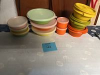 Photo showing a grouping of 11 assorted Tupperware containers and lids in different colors and sizes on a table.