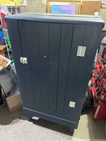 Front view of the vintage handmade wooden cabinet, closed door showing vertical panel design, metal hinges and latch.