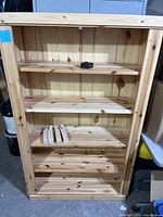 Full front view of wooden bookshelf with shelves and support pieces on the bottom shelf.