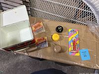 Lot contents displayed showing metal lunch box, two condom packages, two yo-yos, and unopened PEZ dispenser