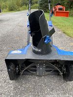 Front view of the blue mini electric snowblower showing the black adjustable chute and metal auger area.