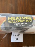 Close-up of the product label showing 'HEATING WALKWAY MAT' in bold letters and mention it melts snow on contact.