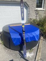 Full view of one Kastle downhill ski standing upright against a hot tub, showing length and general condition.