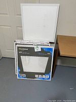 Four total Luminus LED panels shown stacked near a plain white door and brown wooden table. Includes 3 new in box and 1 opened panel.