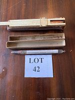 Top-down photo of the slide rule, two wooden cases, and the mercury thermometer, all shown on a wooden surface.