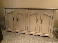 Front view of the painted wood server showing four doors with brass hardware and carved panels, base with curved apron.