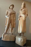 Photo showing both carved wooden figurines, the fisherman and fisherwoman, standing side by side on their wooden bases.