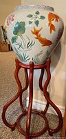 Front view of the koi fish ceramic pot on wooden stand showing the koi and lotus flower design