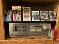 Pioneer CT-F500 cassette deck in wood shelving with various cassette tapes displayed above it including Steppenwolf, Chicago, ABBA, Depeche Mode, and blank tapes.