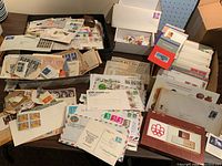 Photo of box with numerous stamps, covers, envelopes spread on table showing quantity and variety