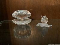 Photo of the Swarovski crystal oyster with pearl and crystal snail figurines side by side on glass shelf.