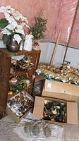 Wide view of wood shelf with angel figurine and Christmas decorations on it, boxes of ornaments beside it, and flowers in the back