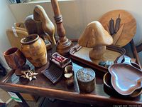 Wooden tray with multiple wooden and ceramic decorative items including vases, candlestick holder, goblet, trinket box, ceramic mushroom, comb, bowls, and wall art.