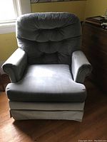 Front view of a blue upholstered swivel chair showing tufted backrest and cushioned seat and arms.