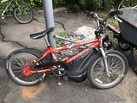 Orange/red boys dirt bike style bicycle with 'Power Zone' branding, black chain guard, knobby tires, and flat black seat. Shows signs of wear.