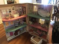 Open townhouse showing interior rooms, furniture including beds, chairs, tables, and accessories arranged on each floor