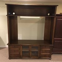 Front view of a walnut-finished hardwood TV/media credenza with two glass doors in the center, surrounded by eight small drawers, and an open shelf above for additional media components or decor. Shows original hardware and wood grain finish.