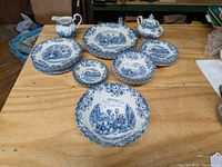 Full set of 25-piece Johnson Bros Coaching Scenes pattern dinnerware arranged on table showing bowls, plates, creamer, and sugar set.