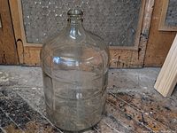 Clear glass 5 gallon carboy standing upright to show overall shape and condition.