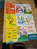 Top-down view of the 9 hardcover Dr. Seuss books laid out on a wooden table, showing all cover art and titles clearly.