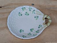 Top view of oval Belleek porcelain butter tray with green shamrock motifs and basketweave texture with handle