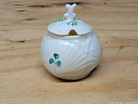 Front angled view of the jar showing the sea shell texture and shamrock decoration on the body and lid.