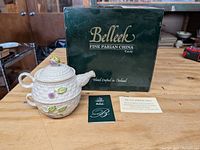 Front view of the tea set with Belleek branded box and certificate cards on a wooden surface