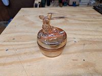 Front view of small iridescent marigold carnival glass powder jar with Scottie dog on lid.
