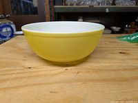 Side view of a vintage yellow Pyrex mixing bowl showing its color and shape.