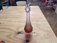 Front angle showing full height and transpinkation of the vase on a wooden table