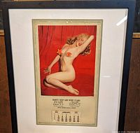 Full framed calendar showing Marilyn Monroe nude pin-up image with two red star-shaped stickers on glass and Jan 1954 calendar below
