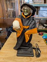 Front view of the witch animation showing the witch holding a skull with detailed facial features and fabric clothing.