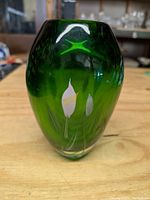 Front view of the heavy green glass vase showing calla lily designs etched or painted on the surface.