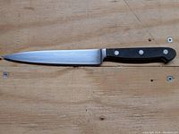 Full view of Henckels slicer knife on wooden surface showing blade and handle.