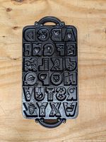 Top view of one cast iron cookie mold tray with alphabet letters and themed shapes