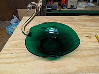 Angled side view of the large forest green swan bowl on wooden surface showing the full swan handle and textured green base bowl.