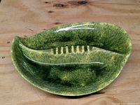 Top angled view of a green ceramic leaf-shaped ashtray showing molded leaf veins and rib detail
