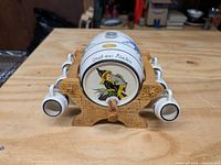 Front of barrel liquor dispenser showing painted Munich figure and text 'Gruss aus München' with 6 shot mugs arranged on wooden stand