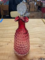 Front view of Rubina Glass cranberry to clear hobnail decanter with clear hobnail stopper and ruffled collar.