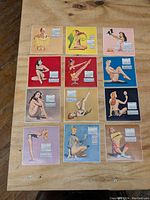 Photo showing all 12 calendar pages with pin-up girl illustrations laid out on a wooden surface.