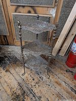 Full view of the 3-tier corner stand showing its overall structure, embossed detail on tiers, and sculpted busts on corner posts