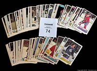 Top view of 74 hockey cards fanned out showing backs and fronts in a semi-circle formation with a card numbered label '74' beside them.