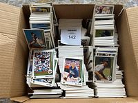 Top-down view of multiple stacks of 1989 Upper Deck baseball cards arranged inside a cardboard box. Several cards are visible on top, showing players in baseball uniforms.