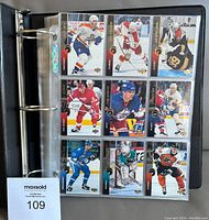 Hole-punched binder pages holding hockey cards in plastic sleeves showing player images, names, teams, and card numbers