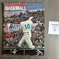 Worn softcover baseball program for the Montreal Expos 1969 season featuring a player at bat on the front cover with writing and date marks.