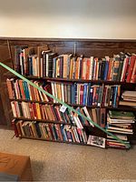 Wide shot showing three shelves of vintage books with various titles and subjects, organized but slightly crowded.