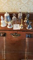 Photo of nine dinner bells displayed on wooden furniture with various sizes and styles