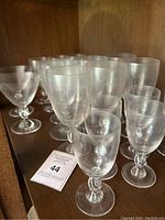 Overall grouping of 22 clear crystal glasses with twisted rope stems displayed on shelf