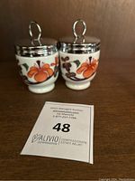 Pair of Royal Worcester Grainger Imari egg coddlers with lids, showing detailed pattern and metal loops on lids.