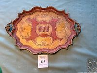Front view of vintage Italian tray showing hand-painted gold and cranberry details with scalloped edges and side handles.